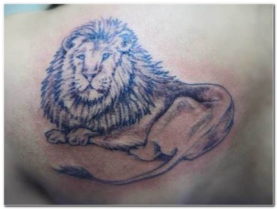 A lion tattoo on man's left shoulder blade.
